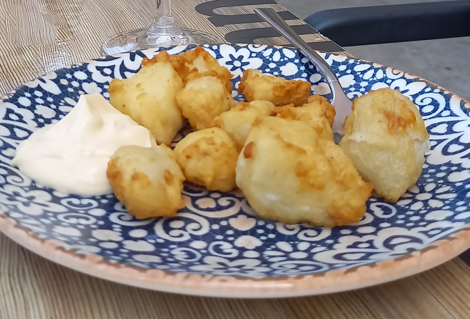 Bocados rebozados con alioli en un plato de cerámica azul y blanca