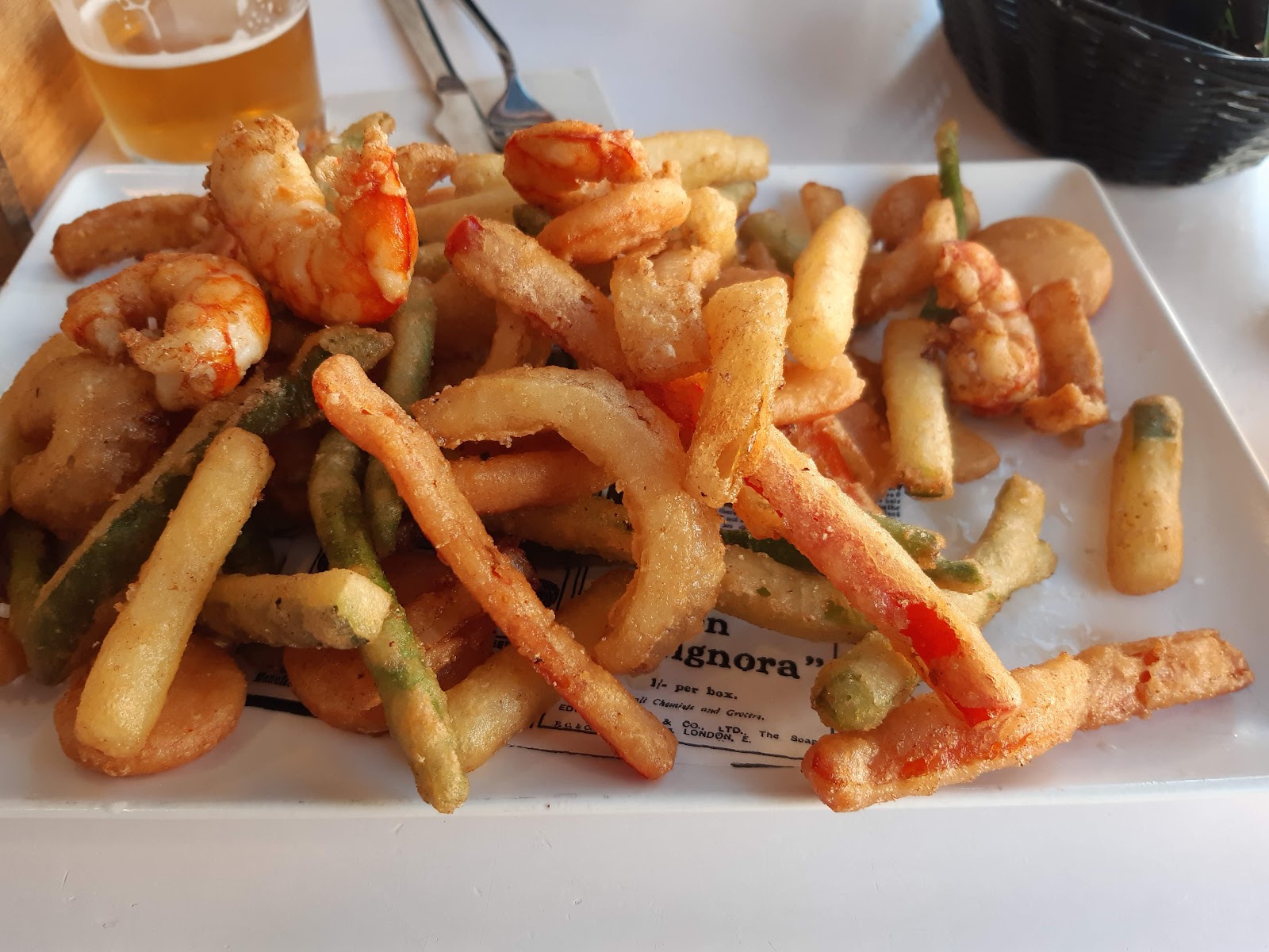 Fritura de gambas, aros y verduras rebozadas en una bandeja blanca