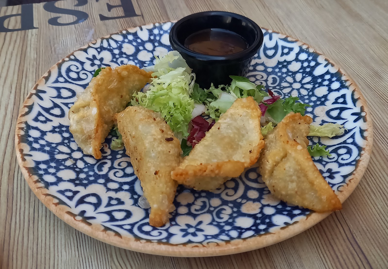 Empanadillas fritas tipo gyoza con ensalada y un cuenco de salsa